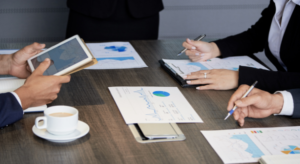 Pessoas com papeis e tablet na mesa